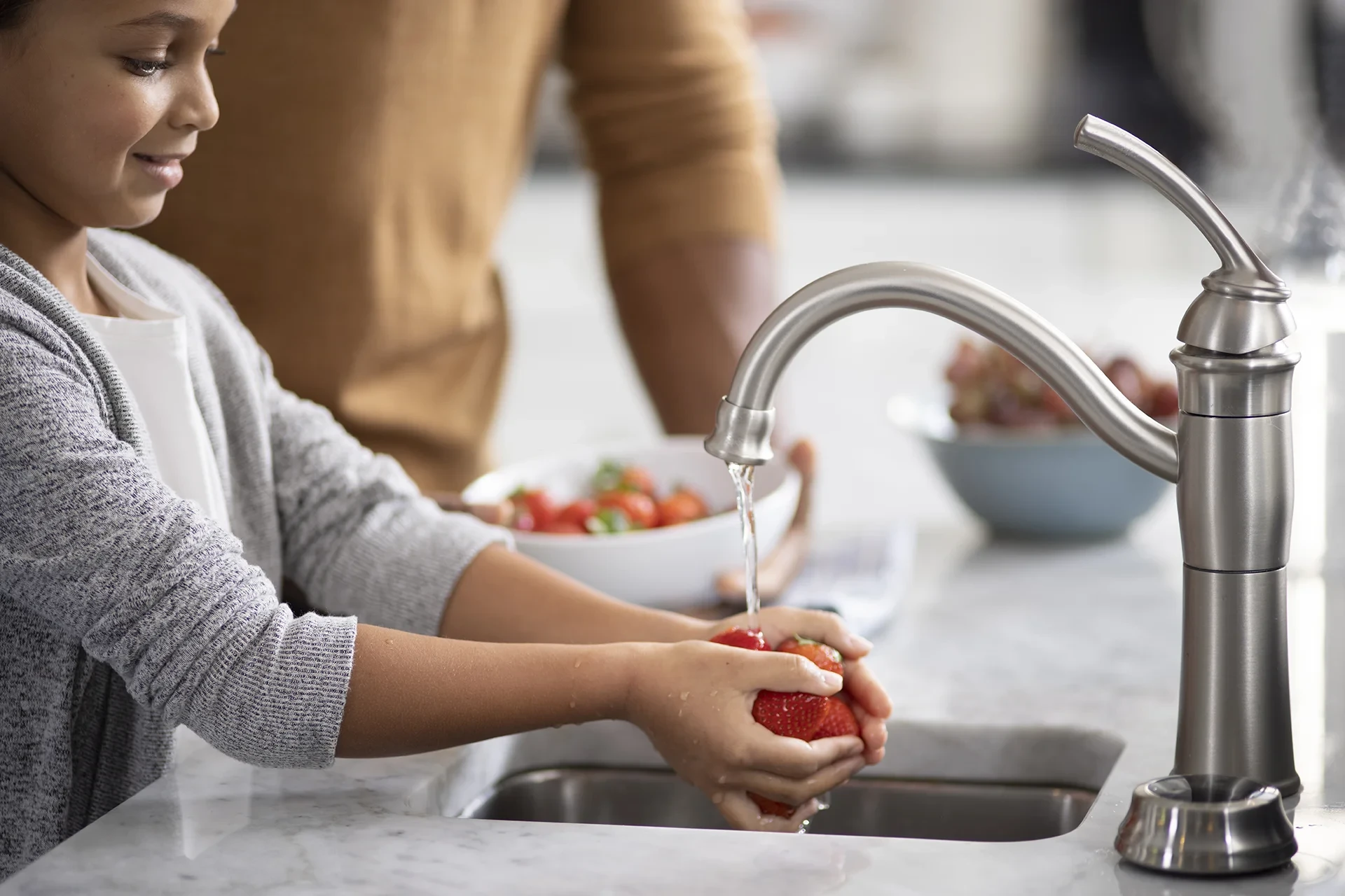 Person washing strawberries in kitchen sink